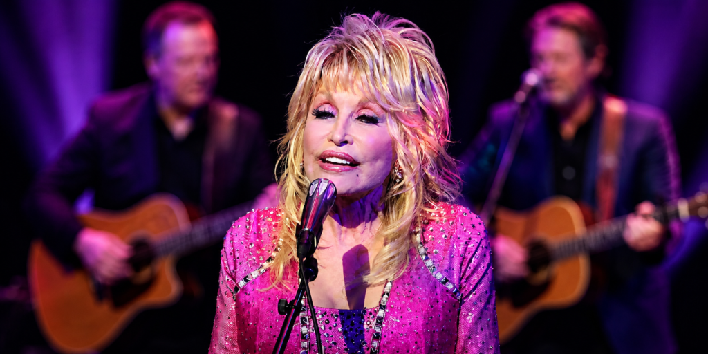 Dolly Parton performing live on stage in a pink outfit during her legendary music career