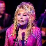 Dolly Parton performing live on stage in a pink outfit during her legendary music career