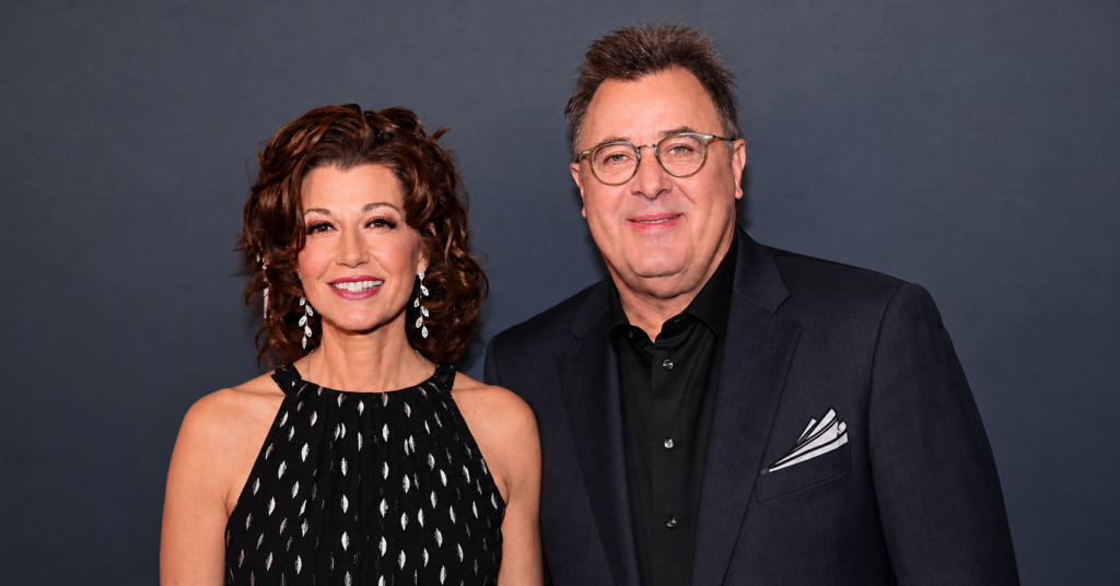 Amy Grant and Vince Gill smiling together at an event as they share their long-lasting love story